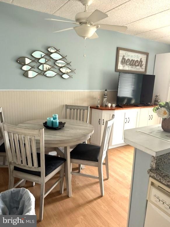 504 E 17th Ave Unit 206, Wildwood, NJ 08260 - dining area with light wood-style flooring, a ceiling fan, and a wainscoted wall