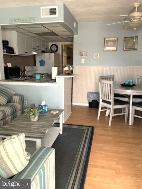 504 E 17th Ave Unit 206, Wildwood, NJ 08260 - living room featuring wood finished floors, ceiling fan, visible vents, and a wainscoted wall