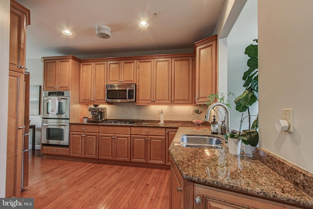 33 Brownstone Dr, East Norriton, PA 19401 - kitchen featuring light wood-style flooring, a sink, dark stone countertops, brown cabinetry, and appliances with stainless steel finishes