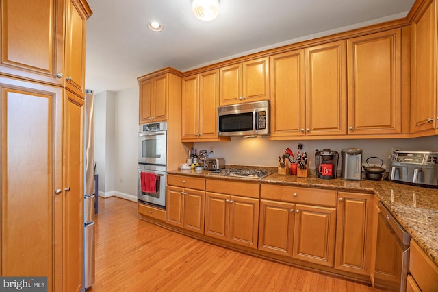 33 Brownstone Dr, East Norriton, PA 19401 - kitchen featuring light wood finished floors, stainless steel appliances, stone counters, and brown cabinetry