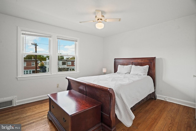 bedroom with wood finished floors, visible vents, a ceiling fan, and baseboards