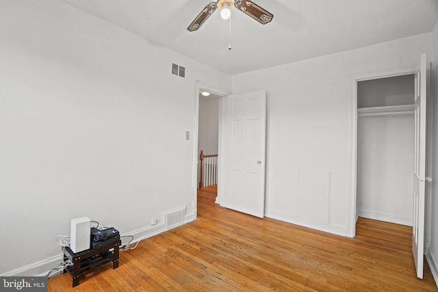 unfurnished bedroom with a closet, wood finished floors, visible vents, and baseboards