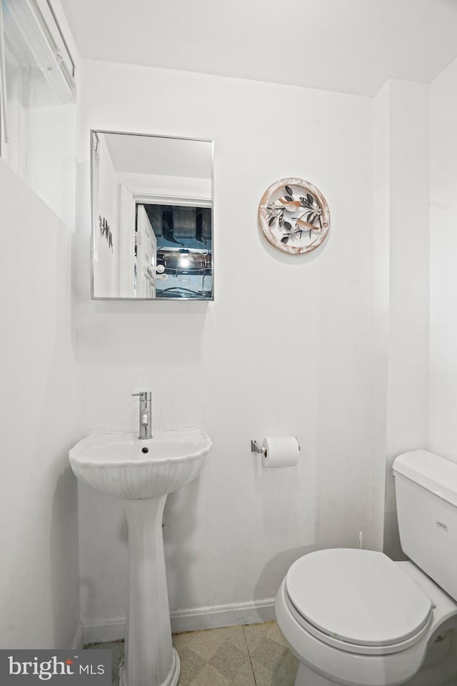 half bathroom featuring baseboards and toilet