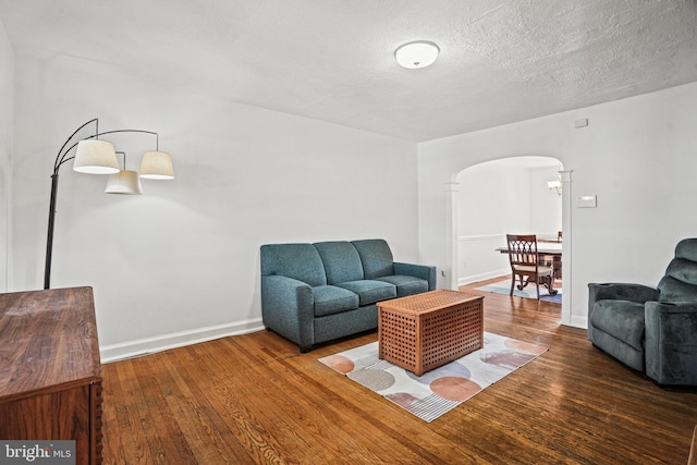 living room with baseboards, wood finished floors, arched walkways, and a textured ceiling