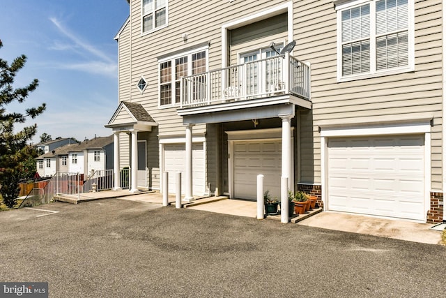 view of front of property with fence, a balcony, and a garage