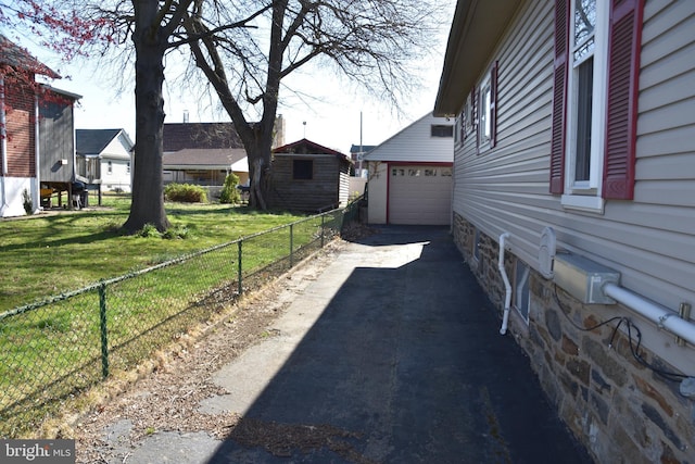 315 Carre Ave, Essington, PA 19029 - view of home's exterior with an outdoor structure, a detached garage, driveway, stone siding, and fence