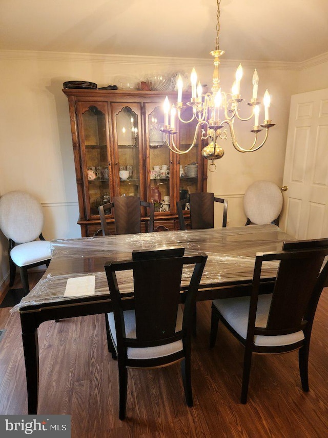 dining room featuring crown molding, a notable chandelier, and wood finished floors