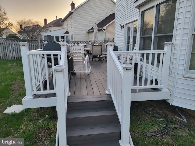 deck at dusk featuring outdoor dining area, french doors, and fence