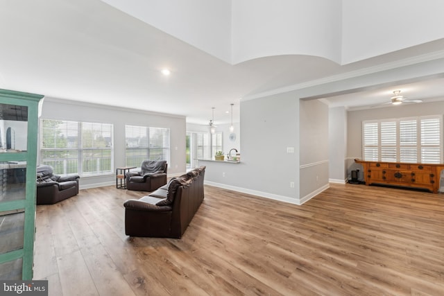 living room with recessed lighting, a ceiling fan, ornamental molding, light wood-style floors, and baseboards