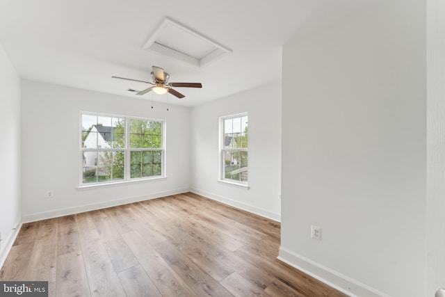 empty room with visible vents, attic access, baseboards, and wood finished floors