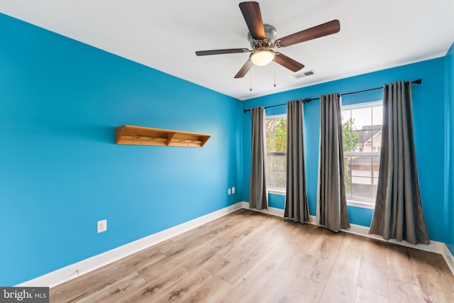 spare room with baseboards, wood finished floors, visible vents, and ceiling fan