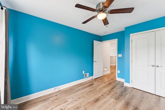 unfurnished bedroom with a ceiling fan, wood finished floors, a closet, baseboards, and visible vents