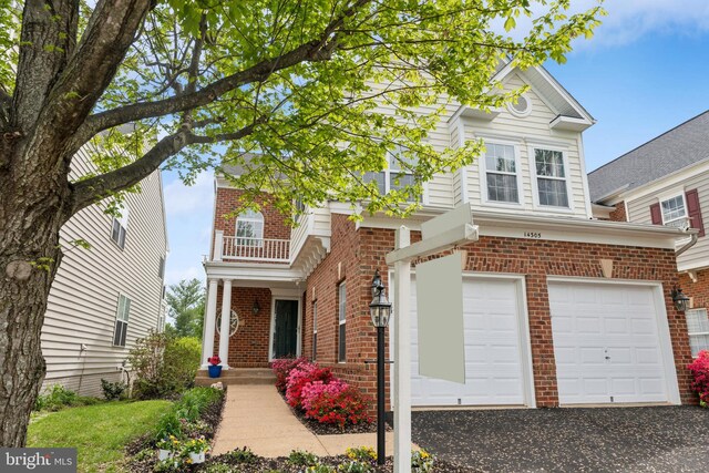 traditional-style house featuring brick siding, a garage, and aphalt driveway