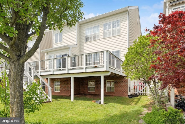 back of house featuring stairs, fence, a yard, a wooden deck, and brick siding