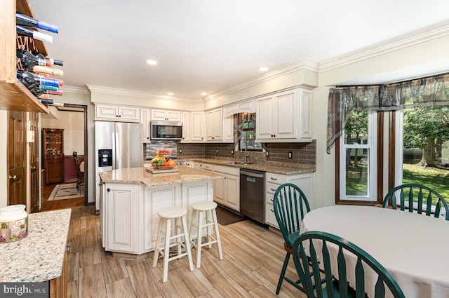 kitchen featuring a sink, appliances with stainless steel finishes, a wealth of natural light, and ornamental molding