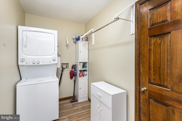 laundry room featuring baseboards, light wood-type flooring, and stacked washer / dryer