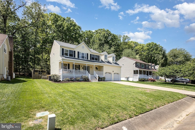 colonial home with a porch, an attached garage, driveway, and a front lawn