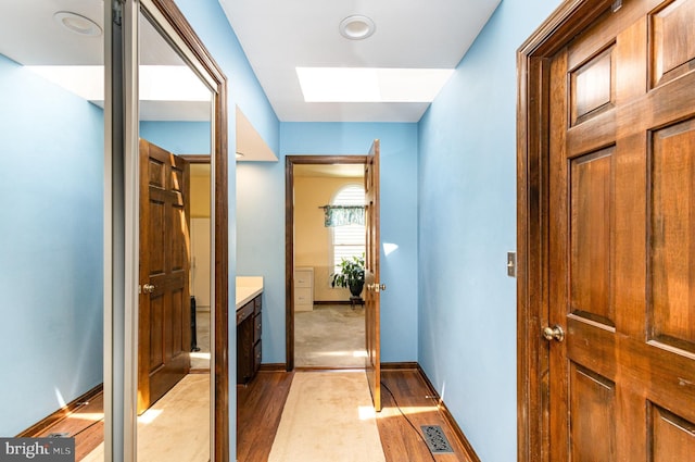 interior space with visible vents, light wood-style flooring, baseboards, and a skylight