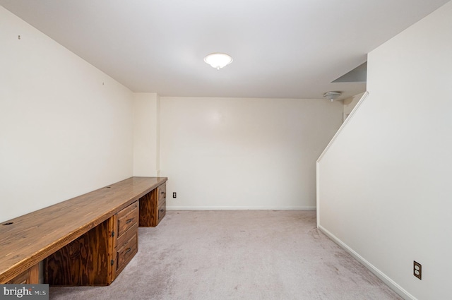 unfurnished office with baseboards and light colored carpet