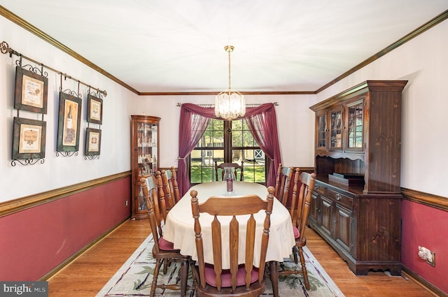 dining space featuring crown molding, baseboards, wood finished floors, and a notable chandelier
