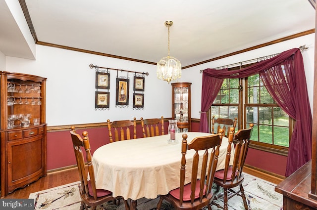dining space with baseboards, ornamental molding, light wood-type flooring, and a chandelier