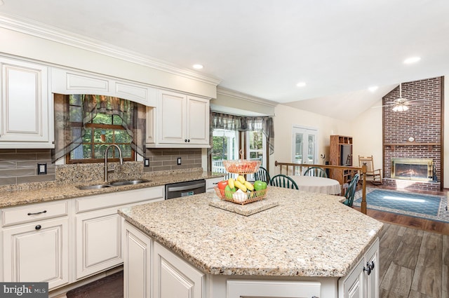 kitchen with a kitchen island, light stone countertops, a sink, and a fireplace