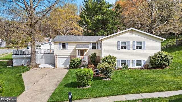 bi-level home with a garage, brick siding, a front yard, and concrete driveway