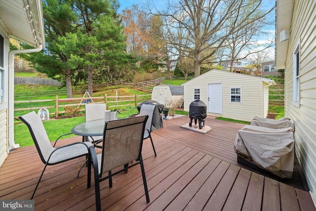 deck featuring a lawn, an outdoor structure, fence, and outdoor dining space