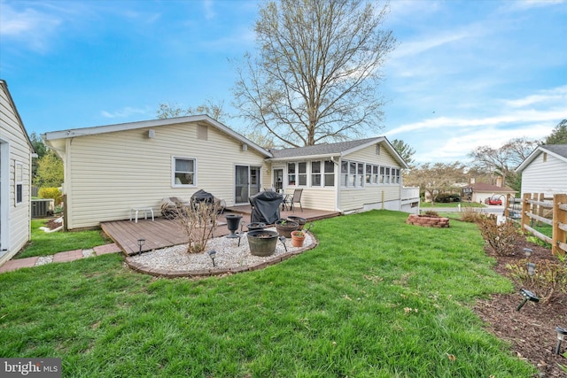 rear view of property featuring a wooden deck, a lawn, central AC, and fence