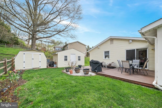 view of yard featuring fence, an outbuilding, outdoor dining area, a storage unit, and a deck
