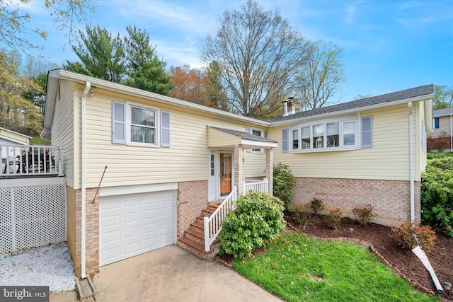 split foyer home featuring concrete driveway, brick siding, a chimney, and a garage