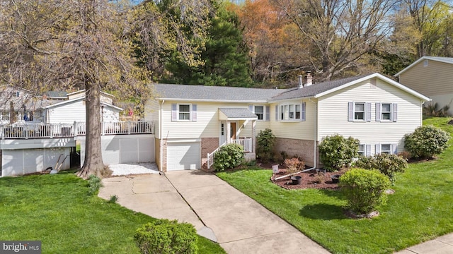 split foyer home featuring roof with shingles, concrete driveway, brick siding, a front yard, and a garage