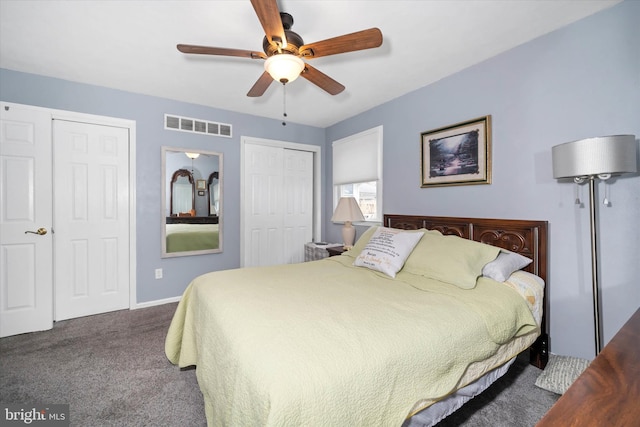 bedroom with carpet, visible vents, a ceiling fan, baseboards, and two closets