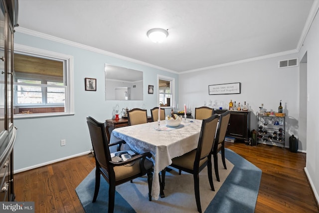 dining room with dark wood-type flooring, visible vents, crown molding, and baseboards