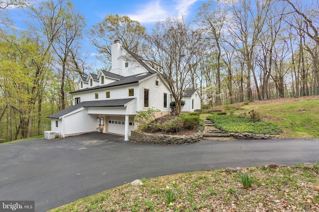2010 Welsh Vly, Malvern, PA 19355 - view of property exterior with a chimney, a shingled roof, an attached garage, and aphalt driveway