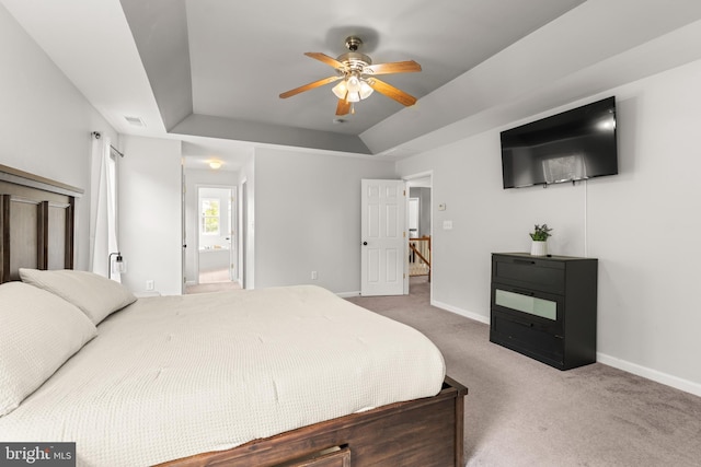bedroom featuring a tray ceiling, carpet flooring, baseboards, and ensuite bath