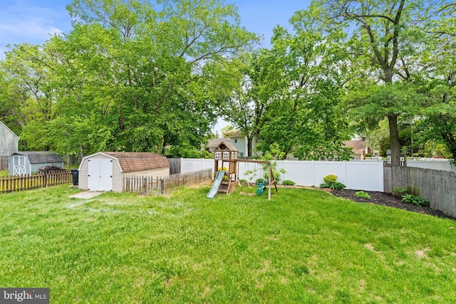 view of yard featuring a storage shed, a playground, and an outbuilding
