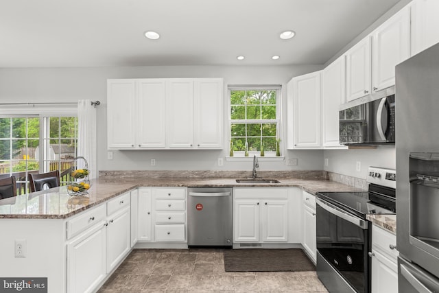 kitchen featuring appliances with stainless steel finishes, a sink, a peninsula, healthy amount of natural light, and recessed lighting