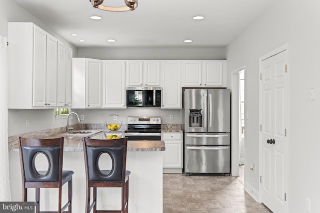 kitchen with stainless steel appliances, white cabinets, a sink, a peninsula, and recessed lighting