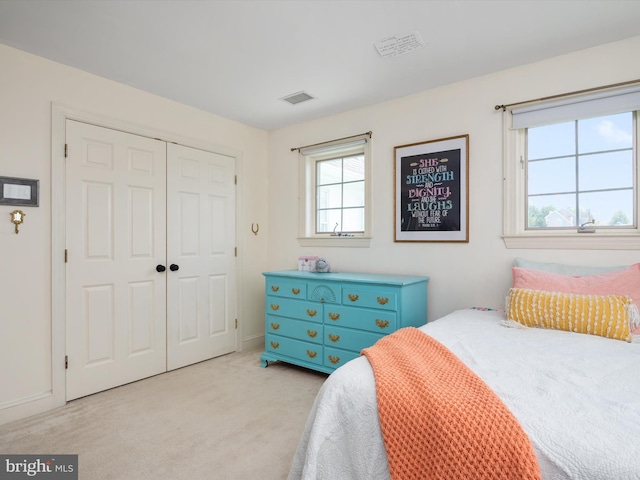 bedroom with visible vents, light carpet, and a closet
