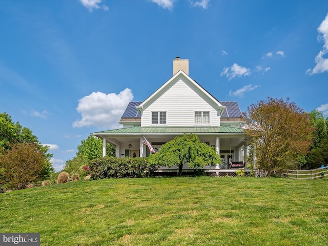 rear view of property featuring a lawn, fence, a chimney, and covered porch
