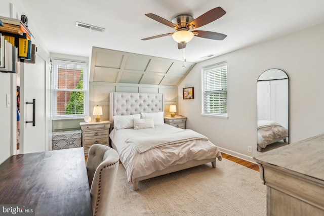 bedroom with baseboards, lofted ceiling, wood finished floors, and visible vents