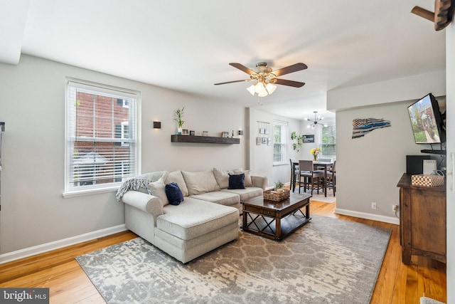 living room with wood finished floors, baseboards, and ceiling fan with notable chandelier