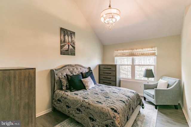 bedroom with wood finished floors, vaulted ceiling, baseboards, and a notable chandelier