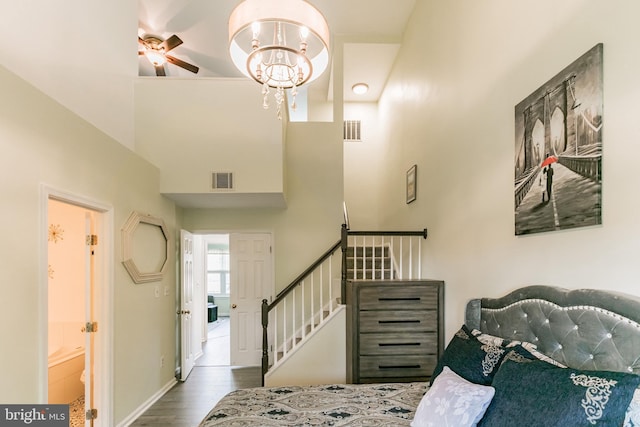 bedroom with a high ceiling, baseboards, wood finished floors, and visible vents