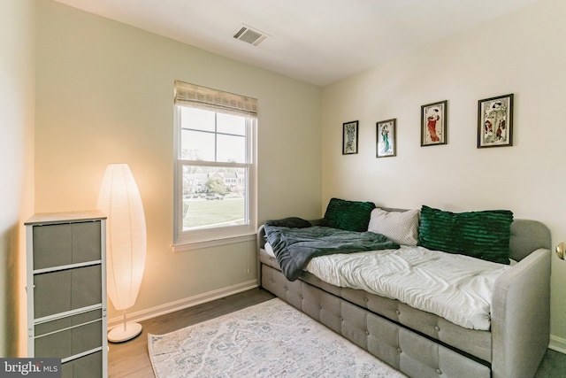bedroom with wood finished floors, visible vents, and baseboards