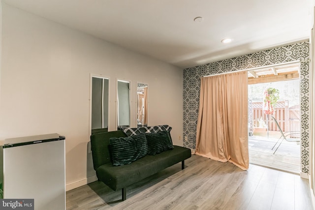 living area with light wood-style floors, baseboards, and wallpapered walls