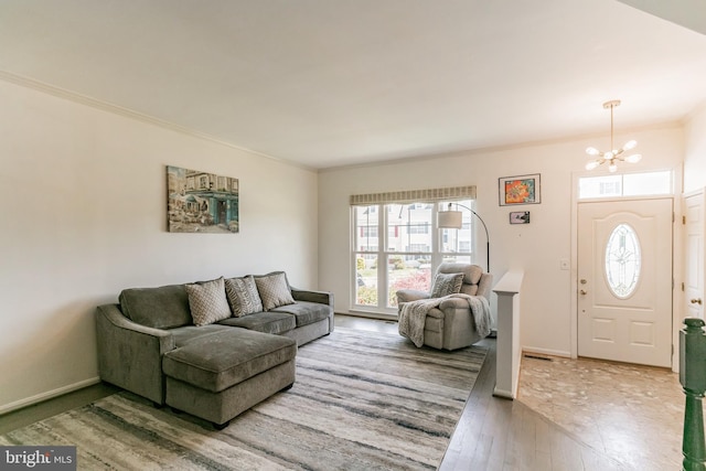 living room featuring light wood finished floors, baseboards, an inviting chandelier, and crown molding