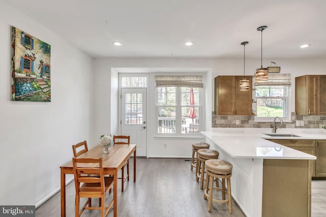 kitchen with light countertops, a sink, light wood finished floors, and a breakfast bar area