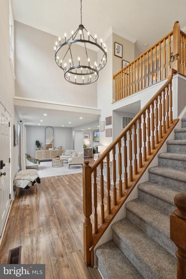 12527 Misty Water Dr, Herndon, VA 20170 - stairway featuring wood finished floors, a chandelier, ornamental molding, visible vents, and a towering ceiling